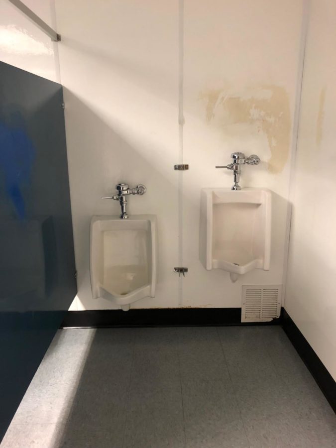 Two urinals right next to each other without any divider between them