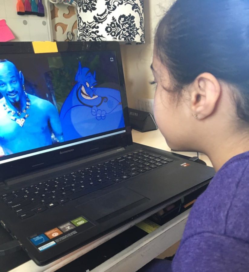 A child comparing photos of the classic animated Genie and the new live action Genie. 
