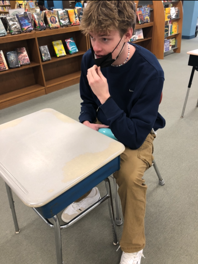Senior Chris Liddell at the Hall Highschool Library during his free period trying to take a quick mask break because he is having trouble breathing.