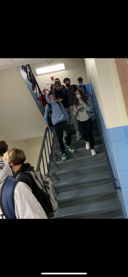 Students disobeying mask requirements while walking down the stairs of Hall High School.