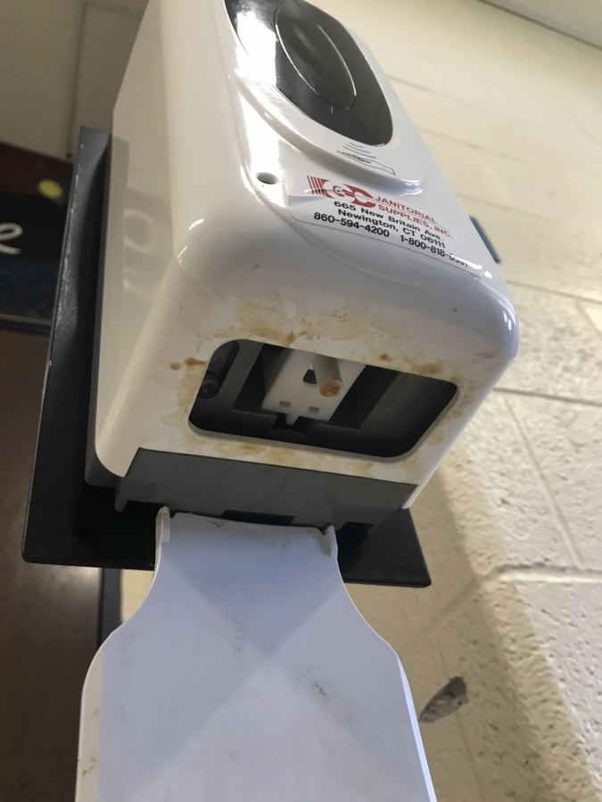 The hand sanitizer dispenser by the entrance near the choir room, with sanitizer residue building up from constant use.