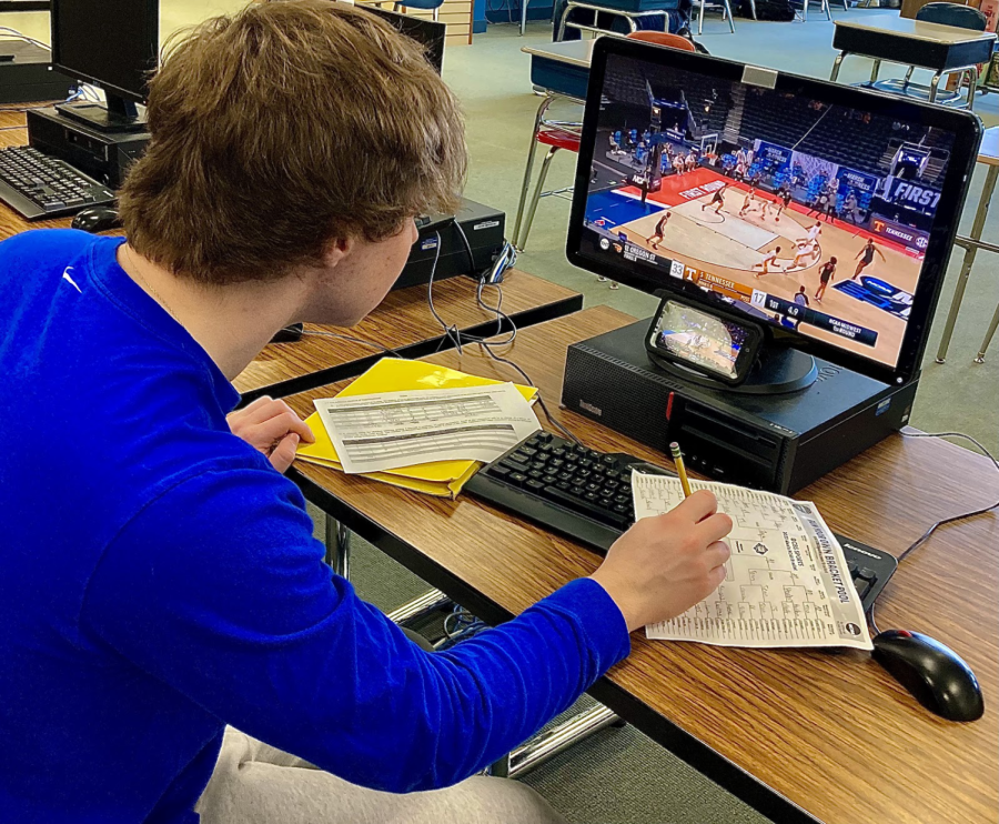 In this picture a student is using the computers in the library meant for studying to fill out a bracket and watch basketball games, while his homework sits unattended in the corner. 
