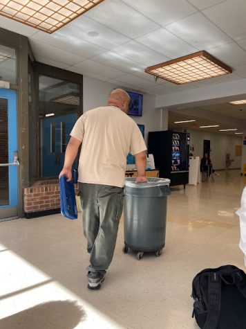 Hall Highs Janitor walking around holding dirty trays and pushing the trash can around the cafeteria during period 5 lunch wave. 