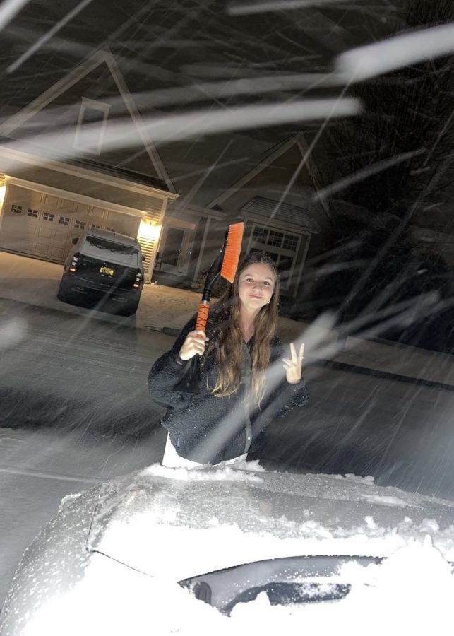 Irene Fotache, Junior at Hall High School, cleans snow off a car mid-snow storm. The process took nearly five minutes to scrape both ice and snow. Friday, March 3rd, 2023 in Bloomfield, CT.