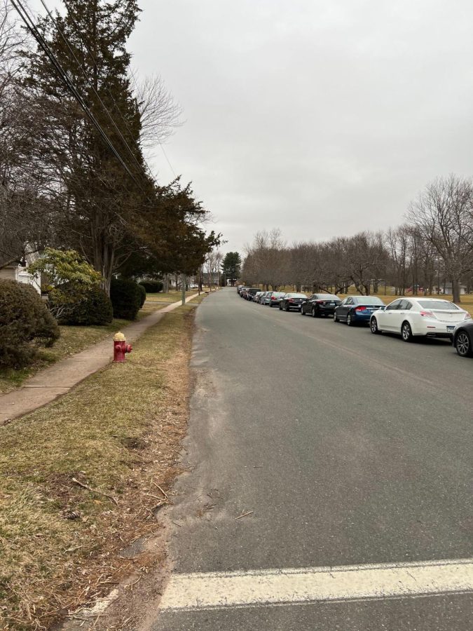Student cars are lined up on a residential street.
