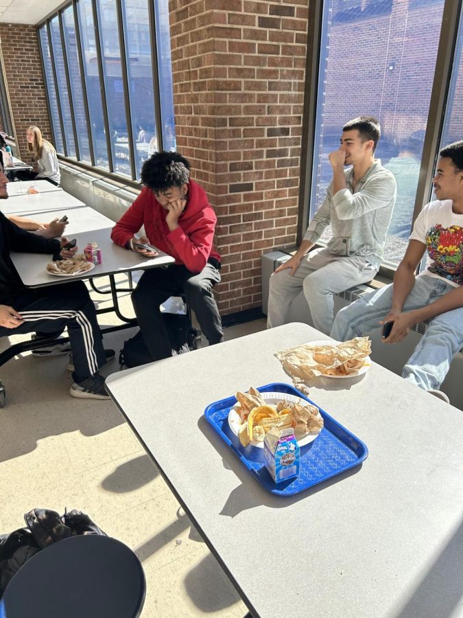 Students sit down trying to eat lunch, but have to sit on the window sill because the table is dirty.
