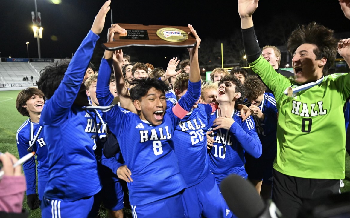 Hall Boys Soccer Team wins the Class LL State Championship and celebrates with the trophy.