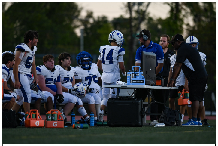 Coach Burke Martindale pictured in blue reviewing film with his offensive players during a game at New Britain.  