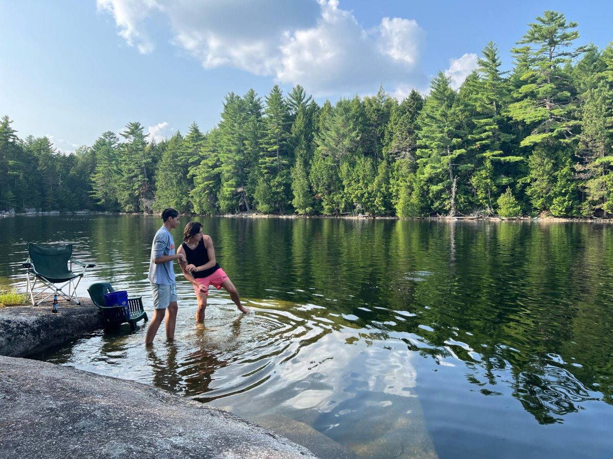 Two teens spend time together lakeside to skip rocks together on a summer day.
