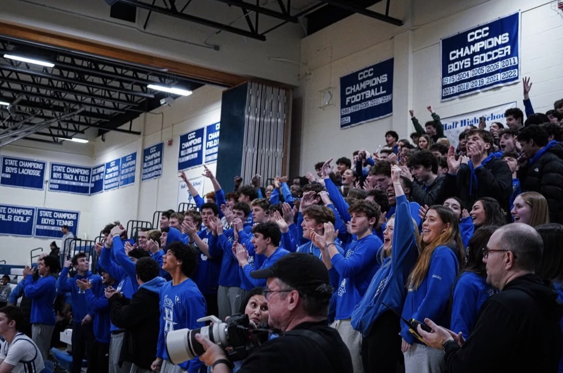 At a basketball game, students from hall high school pack the bleachers,coming together to support their team while having fun with friends and follow the “blue out” themed.